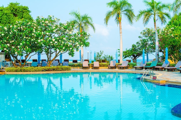 chair pool and umbrella around swimming pool with coconut palm tree - Holidays and vacation concept