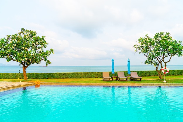 chair pool and umbrella around swimming pool with ocean sea background