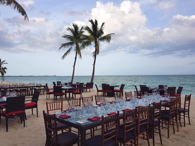 Chairs and tables at beach against sky