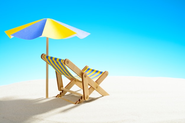 A chaise longue under an umbrella on the sandy beach, sky with copy space