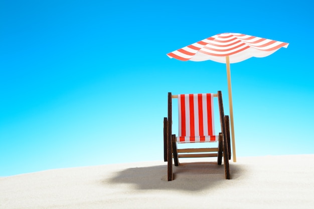 A chaise longue under an umbrella on the sandy beach