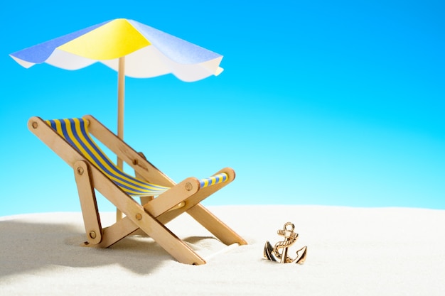 A chaise longue under an umbrella on the sandy beach