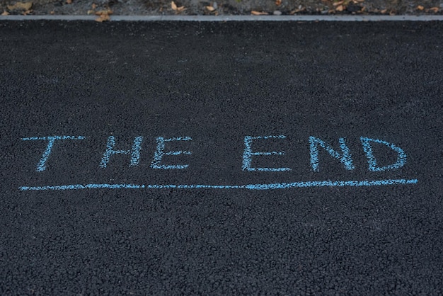 Chalk inscription on asphalt THE END Text on the road Final end of the road concept