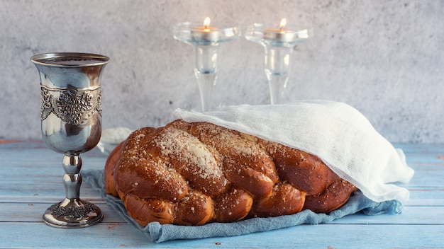 challah bread, shabbat wine and candles on wooden table