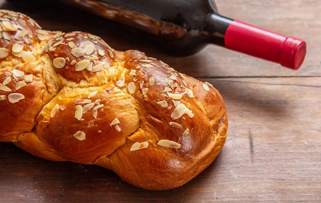 Challah bread with a bottle of red wine on wooden table