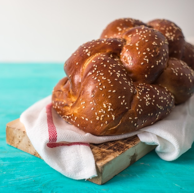 Photo challah bread on a wood plate on wooden table