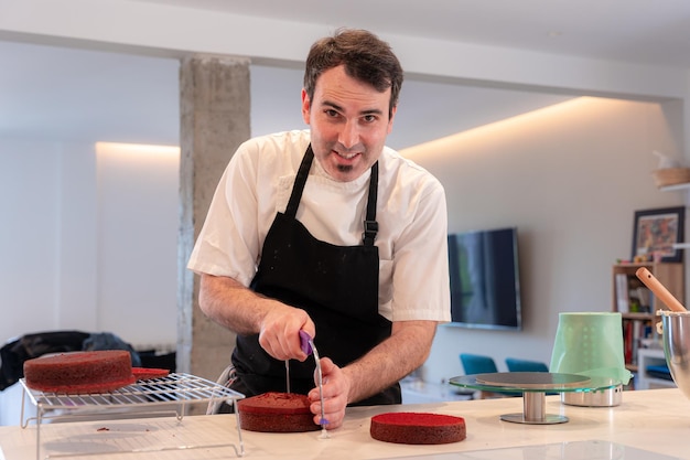 A challenger man cooking a red velvet cake at home cutting the cake baked at home with a lyre