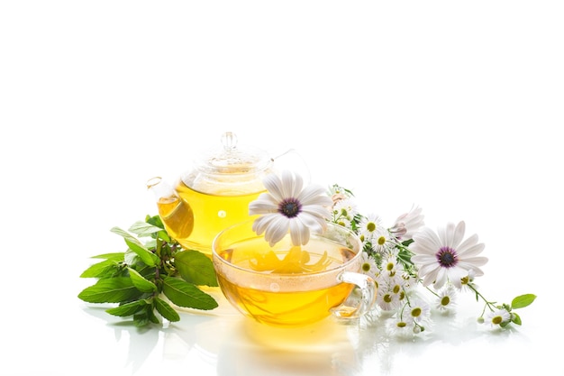 Chamomile flower tea in glass cup and teapot isolated on white background