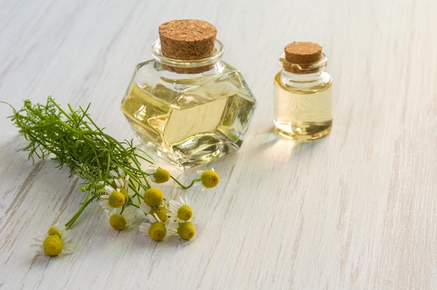 Chamomile flower water or oil in glass bottle on wooden table background