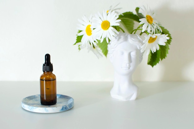 Chamomile flowers and cosmetic bottles with essential oil on a light background Space for text