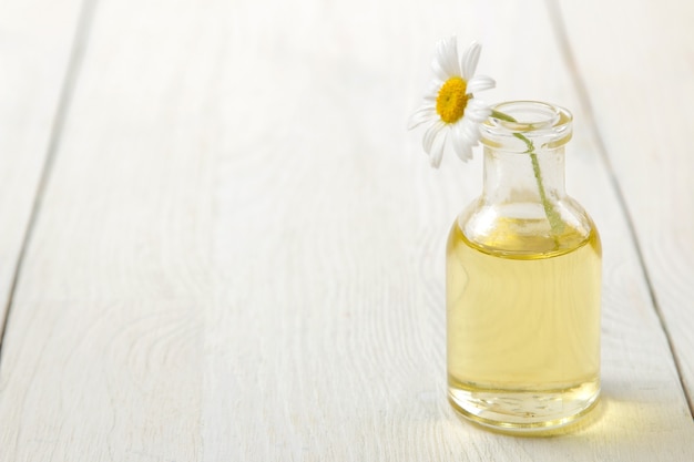 Chamomile. Medicinal little flowers of chamomile with aroma oils on a white wooden table. space for text