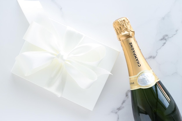 A champagne bottle and a gift box on marble