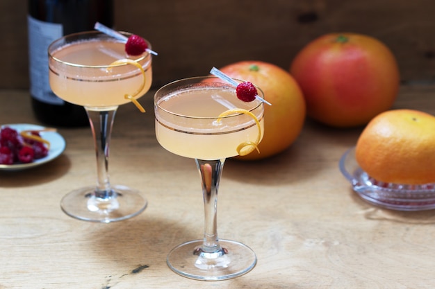 Champagne cocktail with grapefruit juice, garnished with zest and raspberries. Rustic style.