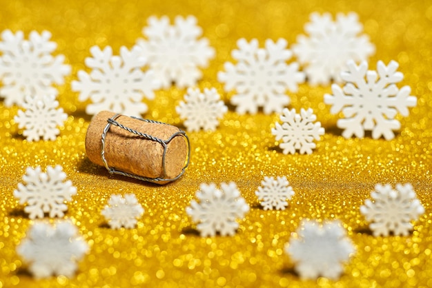 Champagne cork and snowflakes with sparkling glitter on a golden bokeh.