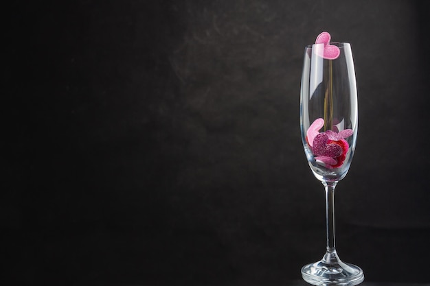 Champagne glass filled with sequin hearts copy space on black background