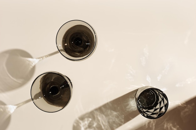 Champagne glasses and glass of water of tinted grey on beige background with hard shadows