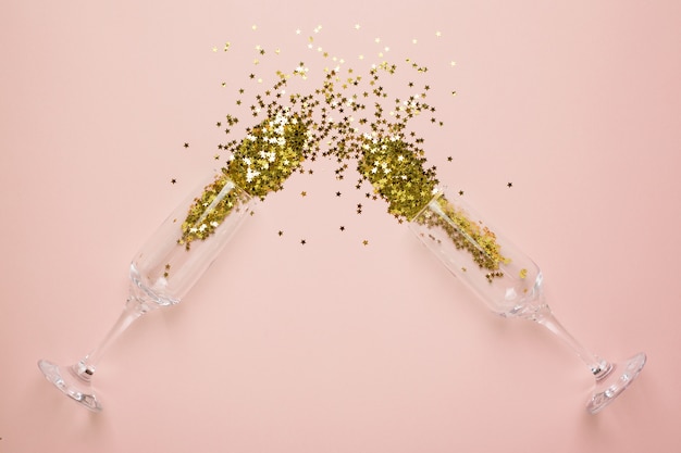 Champagne glasses with golden stars confetti on beige 