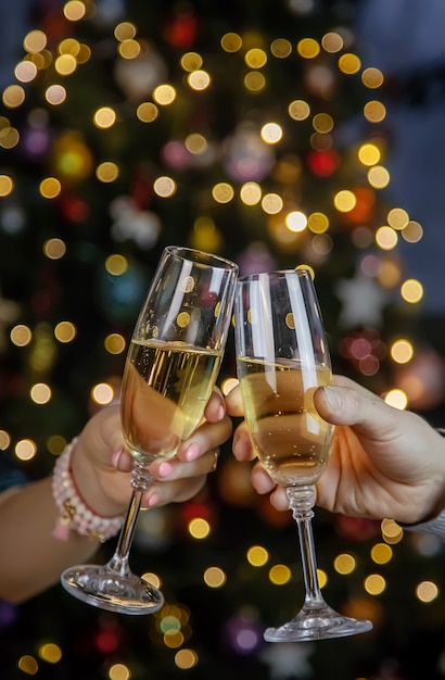 Champagne in hand against the background of the Christmas tree. People. Selective focus. Holiday.