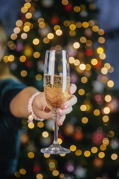 Champagne in hand against the background of the Christmas tree.  