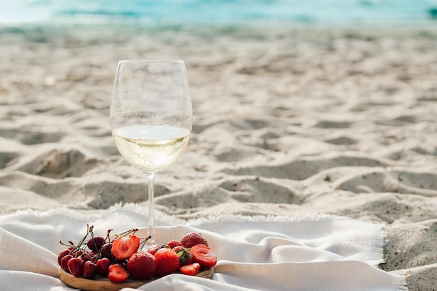 Champagne with fruit tray with strawberries and cherries on a picnic on the beach