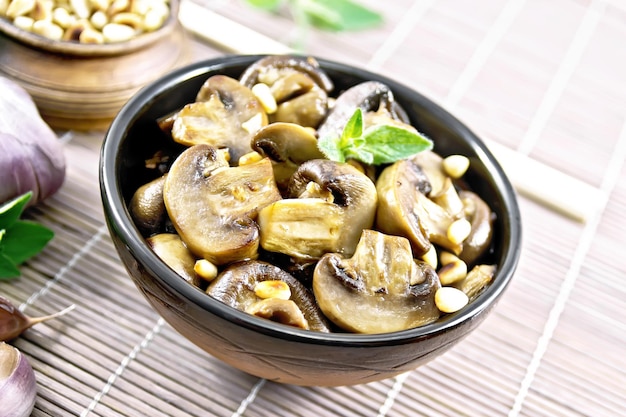 Champignons with oregano and nuts in bowl on bamboo