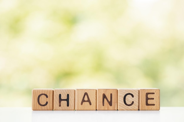 Chance is written on wooden cubes on a green summer background Closeup of wooden elements