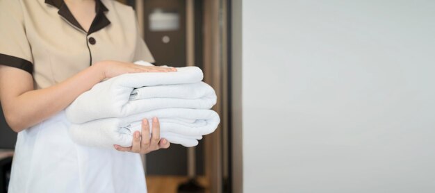 Change of towels in the hotel room A uniformed maid is cleaning up the hotel room