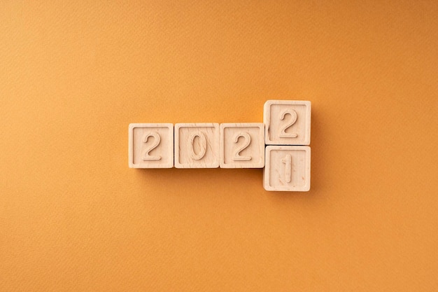 The change of the year from 2021 to 2022 Wooden cubes with numbers on an orange background New Year's card