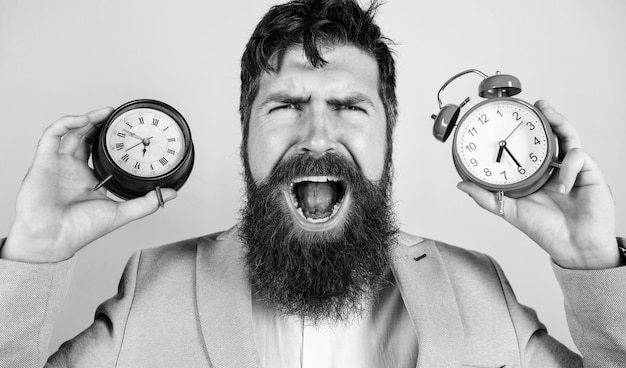 Changing time zones affect health Does changing clock mess with your health Man bearded hipster hold two different clocks Guy unshaven puzzled face having problems with changing time Time zone