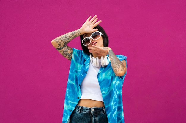 Charismatic brunette young woman from Spain with tattoos in a bright blue shirt posing in a studio