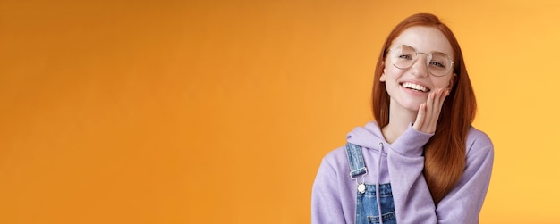 Charismatic happy tender redhead smiling european girl s glasses hoodie denim overalls having fun en