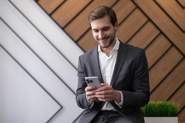 Charismatic young businessman with a phone in his hands with a smile in the office