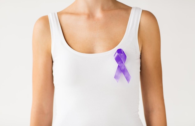 charity, people, health care and social issue concept - close up of woman with purple domestic violence awareness ribbon on her chest