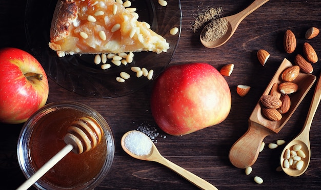 Charlotte with apples and nuts. Preparation of apple baking with nuts and honey. Dessert baked goods from apples and nuts with honey on a wooden table.