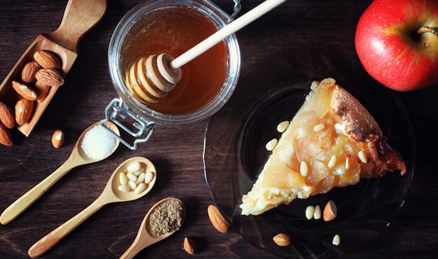 Charlotte with apples and nuts. Preparation of apple baking with nuts and honey. Dessert baked goods from apples and nuts with honey on a wooden table.