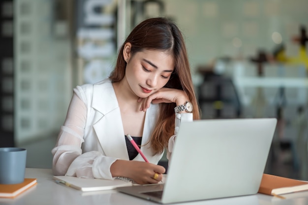 Charming asian businesswoman sitting working on laptop in office.