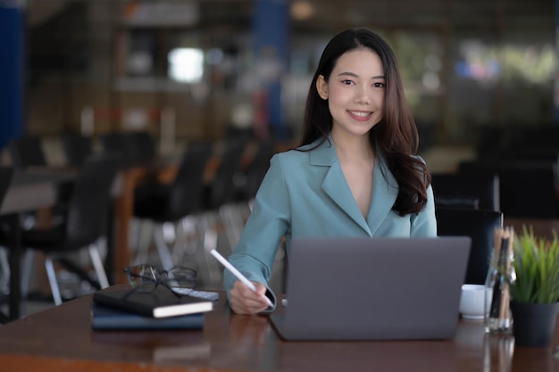 Charming asian businesswoman sitting working on laptop in office.