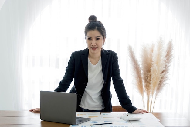 Charming Asian businesswoman with a smile standing smart at the office looking at the camera