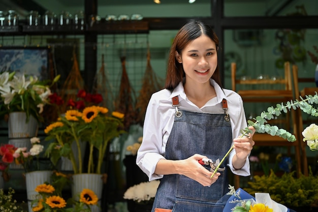 Charming Asian female florist making a bouquet preparing flowers for delivery order