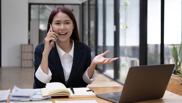 Charming Asian woman with a smile standing holding papers and mobile phone at the office