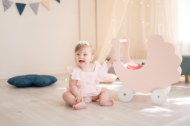 A charming baby girl is playing in a cozy bright children's room with a wigwam and soft toys The interior of the children's room Funny baby in the nursery at home