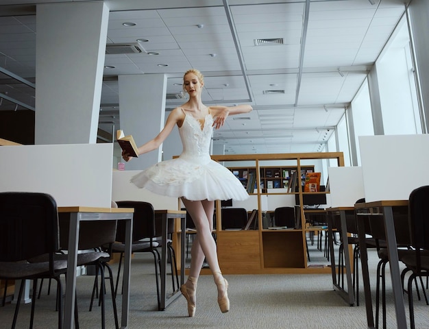 Charming ballerina went to the library to choose a new book during a break showing your stretching and flexibility