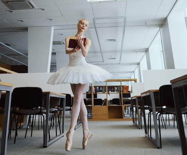 Charming ballerina went to the library to choose a new book during a break showing your stretching and flexibility