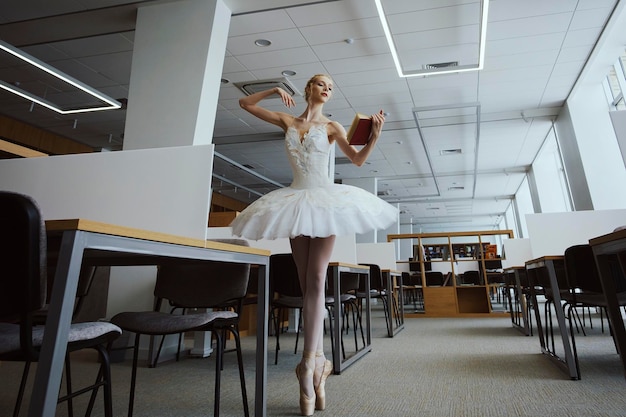 Charming ballerina went to the library to choose a new book during a break showing your stretching and flexibility