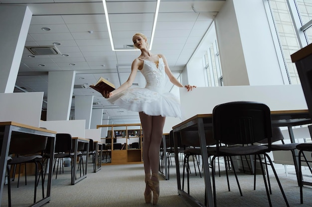 Charming ballerina went to the library to choose a new book during a break showing your stretching and flexibility