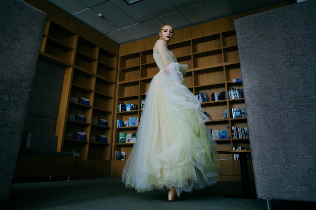 Charming ballerina went to the library to choose a new book during a break showing your stretching and flexibility