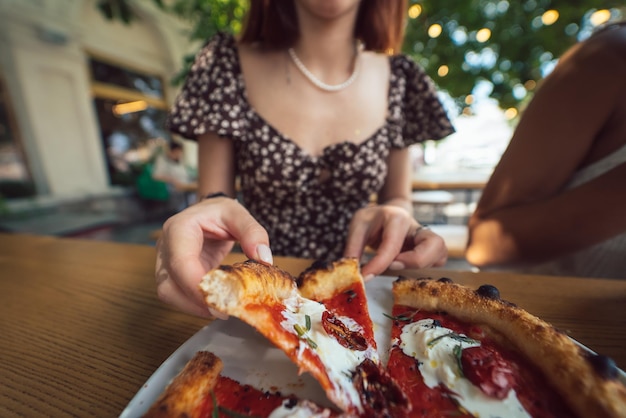 Charming beautiful woman takes a slice of pizza