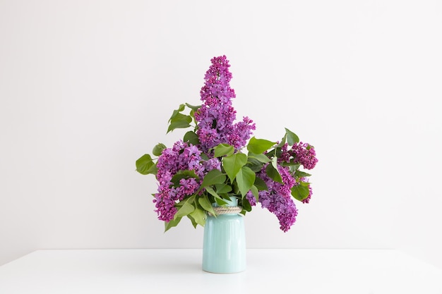 Charming bouquet of blooming lilac in vase on grey