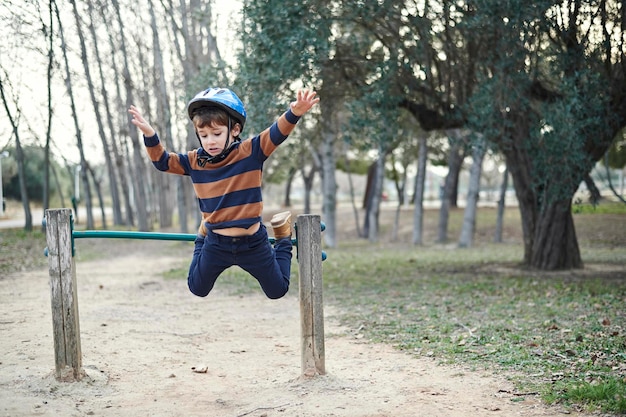 A charming boy plays in the park jumping over obstacles One mistake results in an imminent fall