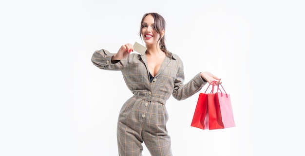 Charming brunette posing in the studio with red packages and a bank card